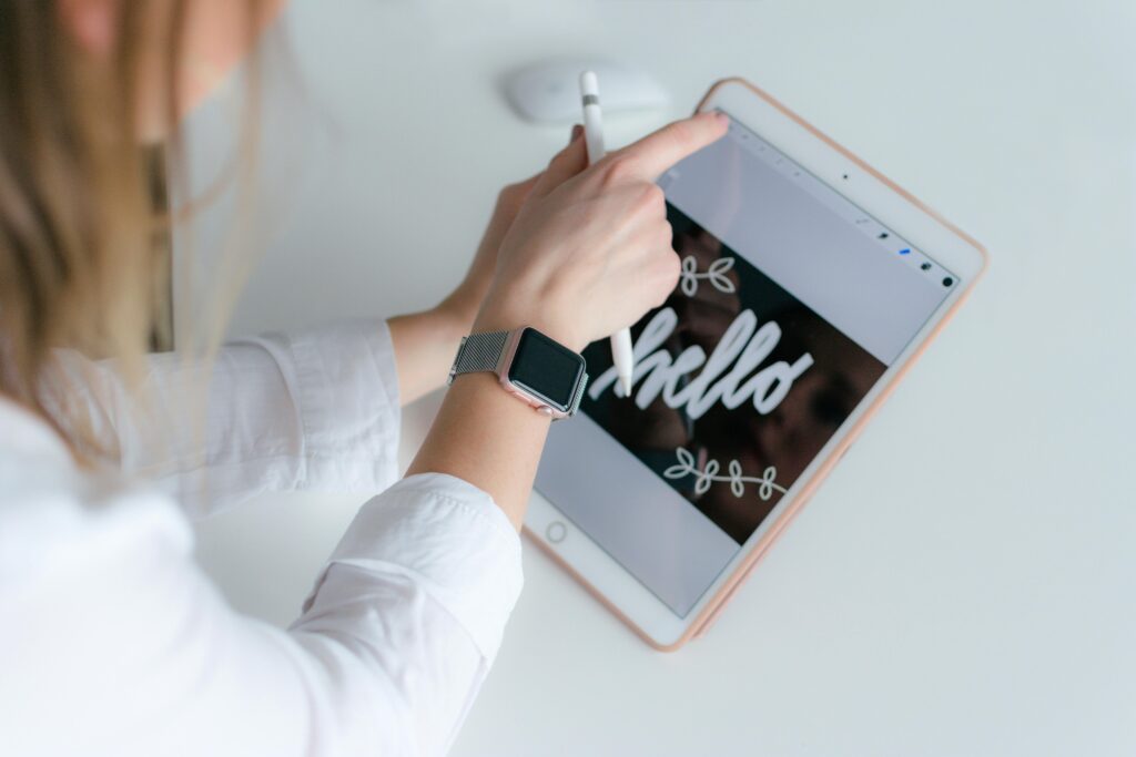 A woman interacts creatively with a tablet and stylus indoors, using technology for design.